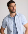 Model is wearing UNTUCKit Dunbar short sleeve shirt in blue and white Dimond print.