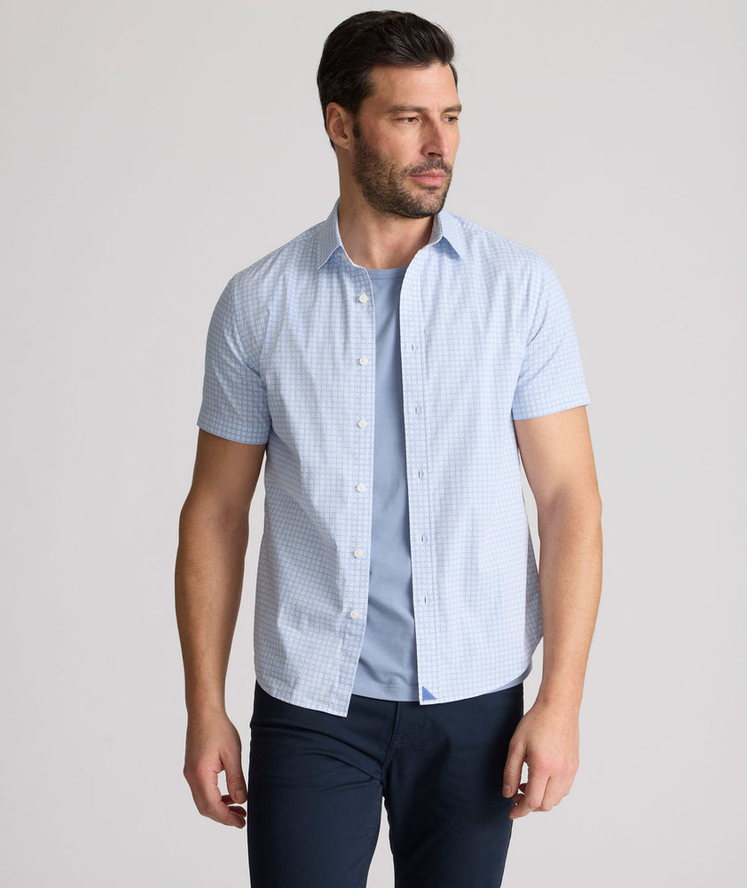 Model is wearing UNTUCKit Dunbar short sleeve shirt in blue and white Dimond print.