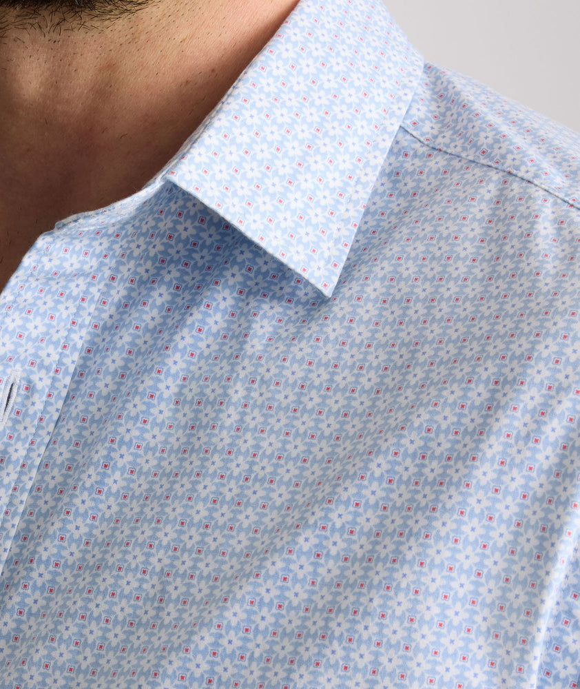 Model is wearing UNTUCKit Dunbar short sleeve shirt in blue and white Dimond print.