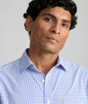 Model is wearing UNTUCKit Kaleb long sleeve performance shirt in light blue and white check.