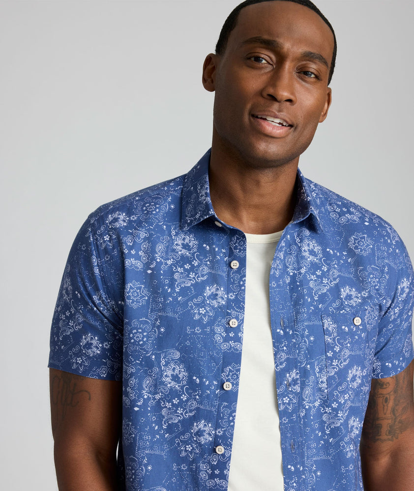 Model is wearing UNTUCKit Monroe cotton linen short sleeve shirt in blue print.